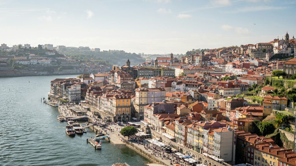 Panoramic view of Porto’s historic center from the Douro River with colorful houses, hills, boats, and Ribeira waterfront