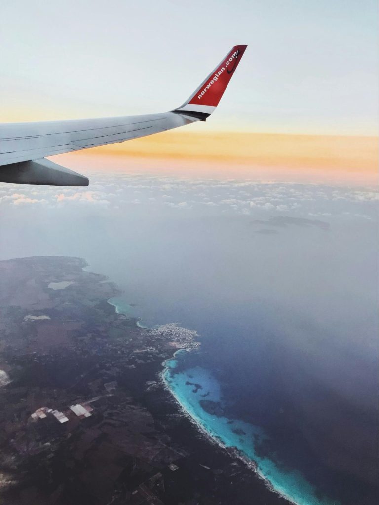Airplane wing over Mallorca coastline aerial view