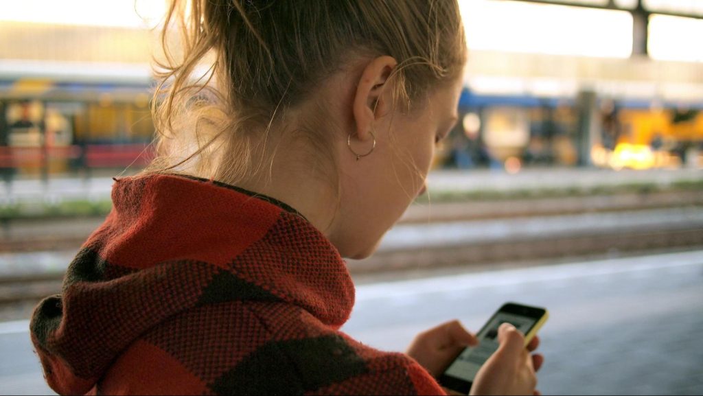 Traveler checking phone at train platform